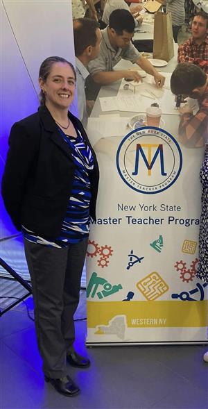 Hannah Wawarski stands beside Master Teacher signage.